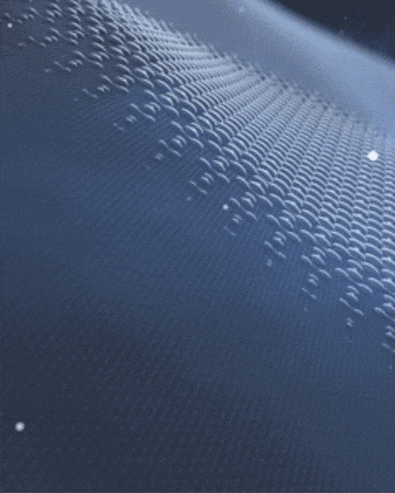 A digital wave pattern flows smoothly, with shimmering, reflective light creating the appearance of small, rippling mounds across a dark blue surface, evoking a sense of motion and fluidity.