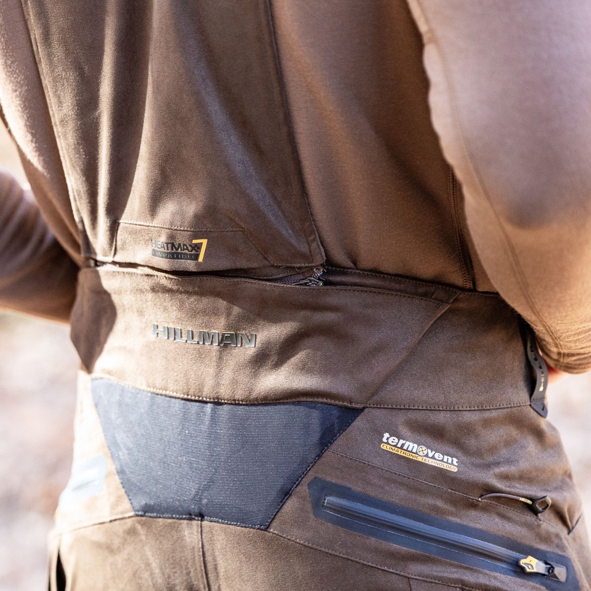 Close-up of a person wearing Hillman’s Cold Weather Camo Pants - Winter Hunting AlphaShell | 6OL, highlighting detailed stitching and logos on the back and waistband—ideal for those seeking insulated outdoor gear.