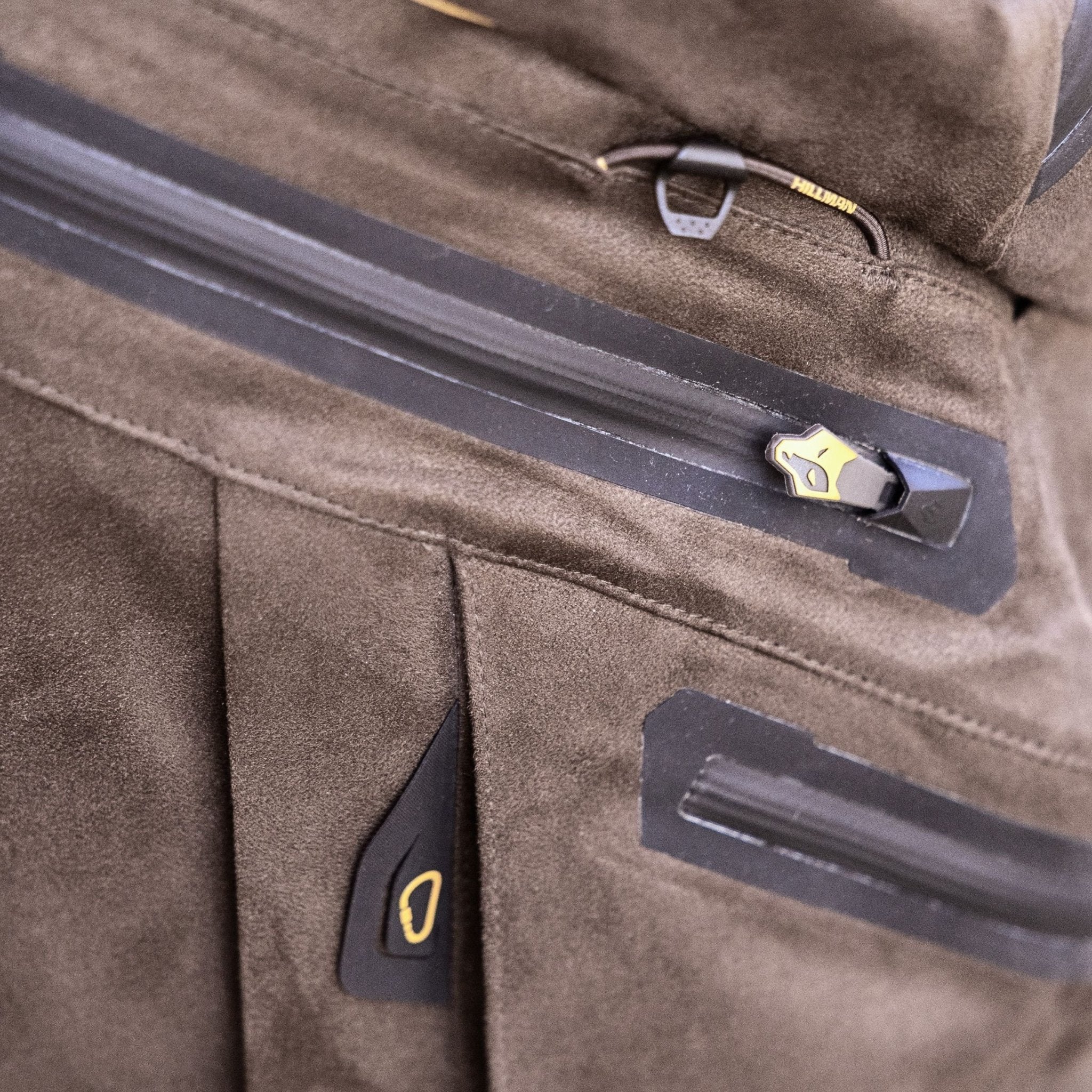 Close-up of a brown suede jacket with a water-resistant zipper and gold-black pull tab—pairs perfectly with Hillman's Cold Weather Camo Pants - Winter Hunting AlphaShell | 6OL for ultimate outdoor comfort. The soft, textured material adds style and warmth.